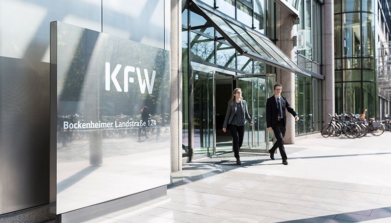 Zwei Mitarbeiter kommen aus dem Eingang der Nordarkade der KfW Zentrale in Frankfurt.